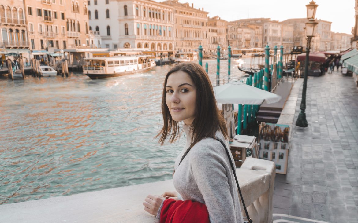 A girl in the short brown hair smiling in front of the Grand Canal in Venice. 