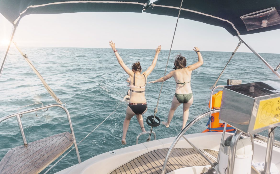 Two girls jumping off the boat to the sea. 